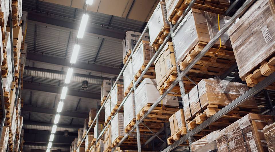 A warehouse with racks of packed boxes to the ceiling