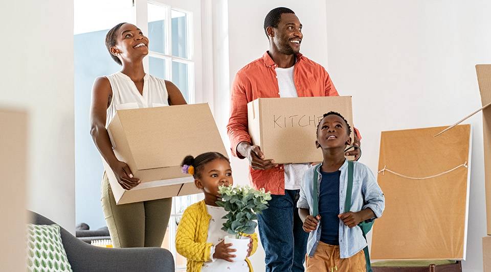 A happy family moving into their new home along with their boxed-up possessions